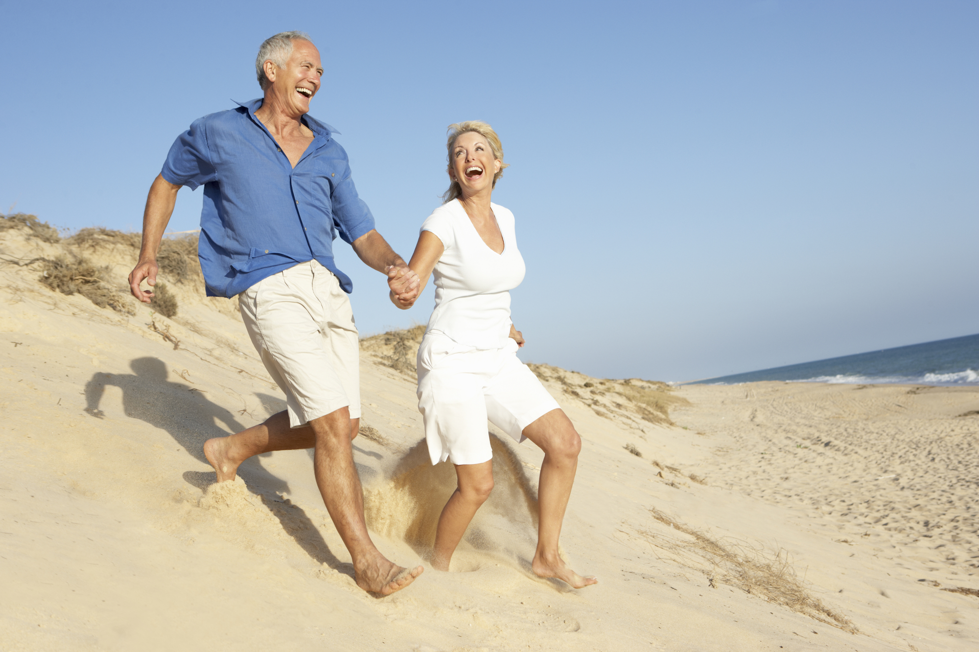 Old couple running on the sand. Want to stay active when you are old? Keys to aging with grace.