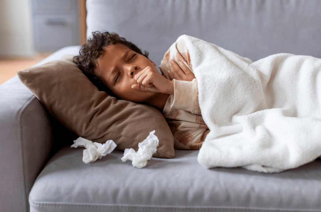 A child laying on his side coughing with Whooping Cough